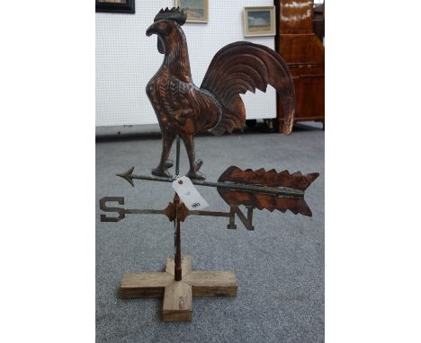 A copper coloured metal weather vane with Cockerel finial over an arrow and directional pointers, mounted on a wooden base. 8