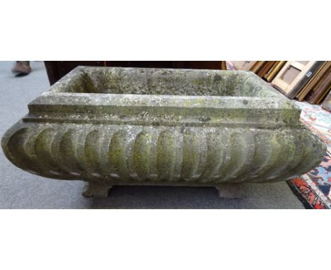 A rectangular carved stone trough, of fluted sarcophagus form, on block feet, 79cm wide x 37cm high x 50cm deep.