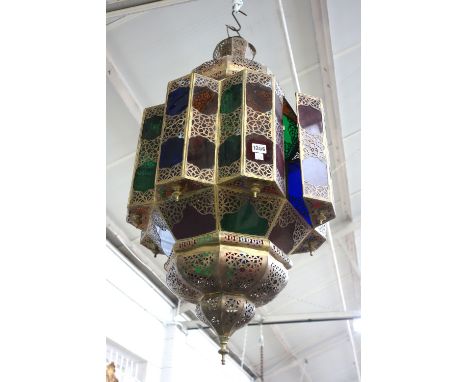 A Middle Eastern sheet metal and coloured glass hanging lantern, late 20th century, of pierced octagonal form with domed ends
