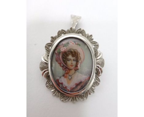 A white gold oval pendant brooch, the centre glazed with the portrait of a lady wearing a hat with flowers, the mount decorat
