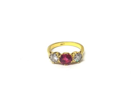A gold, synthetic ruby and diamond set three stone ring, claw set with the circular cut synthetic ruby at the centre, between