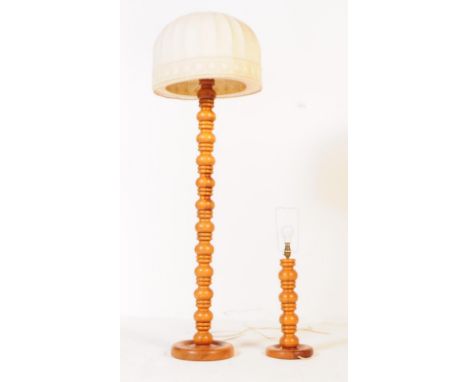 A contemporary blond wood floor standing lamp. The lamp having turned column with bulbous repeating forms, having arched bell