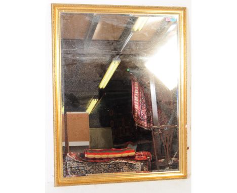 A large vintage 20th century gilt frame over mantel mirror. Having an ornate gilt frame with repeating geometric pattern with