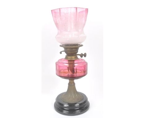 A 19th century Victorian oil lamp. The oil lamp having a Nouveau inspired base with cranberry glass reservoir and tulip shade