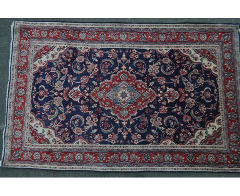 A vintage 20th century North West Persian Sarouk carpet floor rug. Having a red central medallion in a blue ground with flora