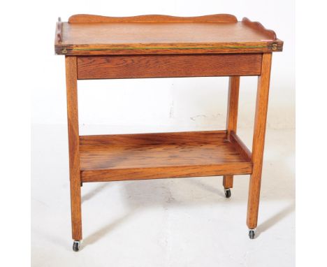 A vintage 20th century oak portable games trolley / table. Rectangular form with curved gallery top with fold over top reveal