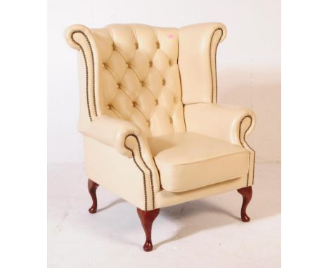 A contemporary Queen Anne revival leather button back armchair. The armchair having a wingback design, with white leather but