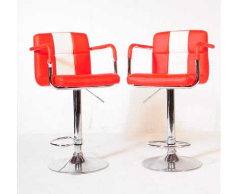 A pair of mid 20th century circa 1970s red and white vinyl and chrome bar stool chairs. The chair having vinyl red box cushio