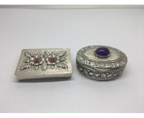 A Continental silver box the top inset with an amethyst cabochon and one other with red stone inset tops with floral repousse