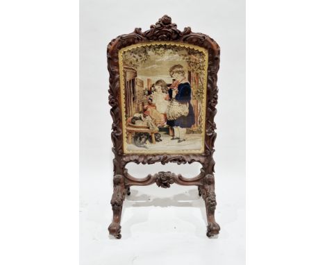 Victorian mahogany firescreen, the surround with heavy foliate scroll carving and floral crest and raised on four carved spla