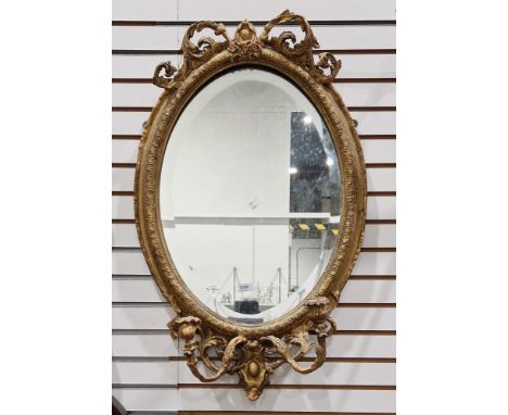 19th century giltwood and gesso oval girandole mirror, the frame with foliate scroll cresting and moulded edge and two fixed 