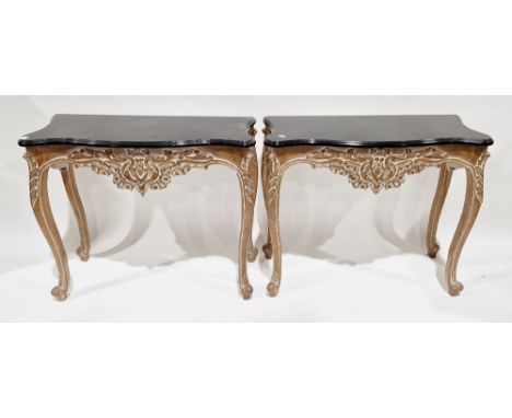 Pair of 20th century console tables in the French Louis XV manner, each with a shaped top with black finish, over a moulded c