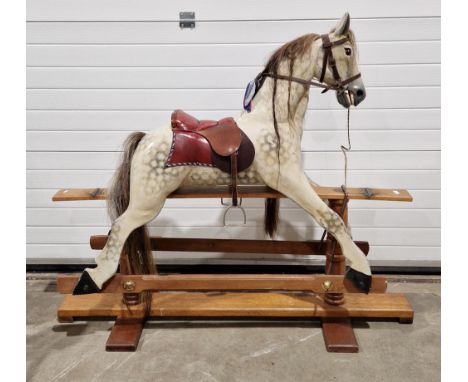 Wooden painted dapple grey rocking horse with horse hair mane and tail and leather bridle and saddle held a hardwood trestle 