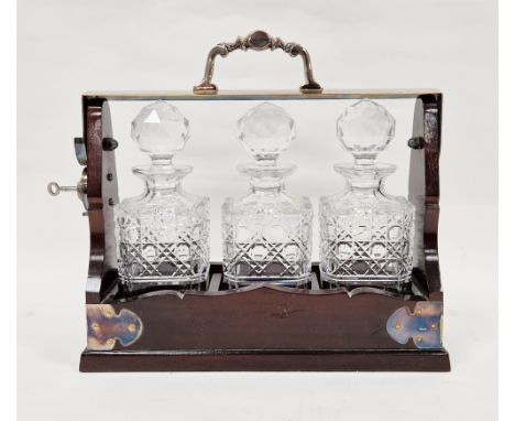 Early to mid 20th century mahogany and silver plated tantalus holding three matching hobnail cut square glass decanters with 