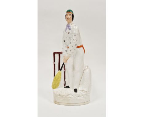 Staffordshire pottery figure of a cricketer, circa 1865, modelled standing wearing a green cap and flowered shirt, holding hi