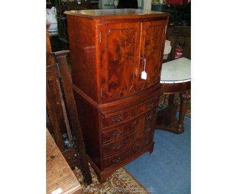 A reproduction Yew finish bow fronted Cocktail Cabinet, the moulded edge cross-banded top over a pair of opposing single burr