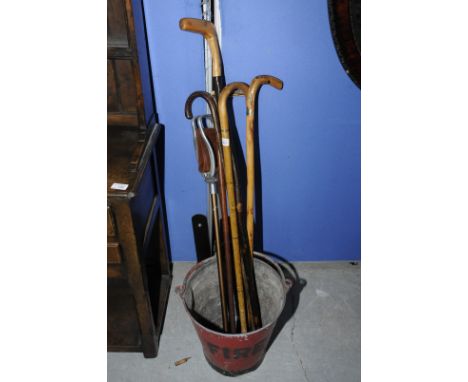 Galvanized fire bucket and a selection of walking sticks and a shooting stick  