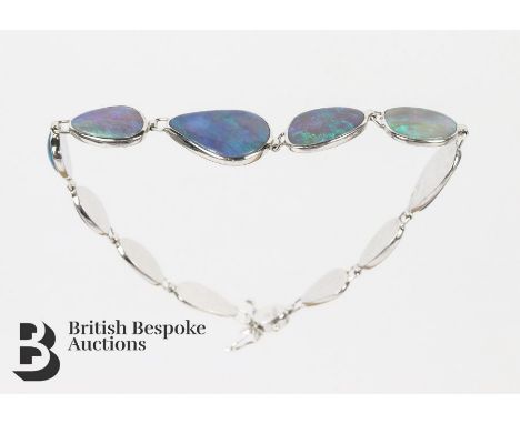 14ct white gold and black opal bracelet. The bracelet set with eleven graduated opals measuring from 10 mm to 15 mms d, appro