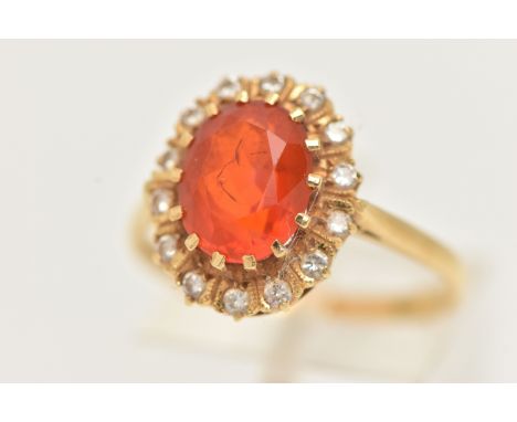 AN 18CT GOLD GEM SET RING, an oval cut fire opal, set with a surround of round brilliant cut diamonds, prong set in yellow go