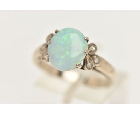 AN OPAL RING, an oval opal, approximate length 10.5mm, prong set in white metal, flanked with six single cut diamonds, scroll