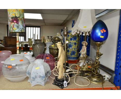 A GROUP OF SEVEN LAMPS AND GLASS SHADES comprising two brass paraffin lamps, two brass electric lamps, one lamp with a resin 