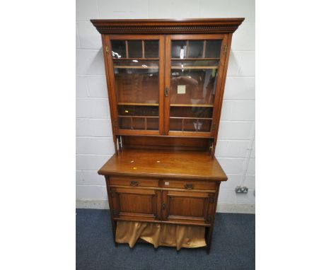 AN EARLY 20TH CENTURY WALNUT BOOKCASE, the double glazed doors enclosing two adjustable shelves, raised on turned supports, a