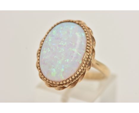 A 9CT GOLD SYNTHETIC OPAL RING, large synthetic opal cabochon, collet/claw setting within a fine rope twist surround, pinched