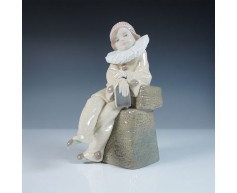 This Lladro figurine, titled Little Jester (#1005203), portrays a young jester seated on a textured stone pedestal, holding a