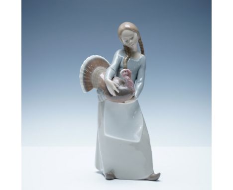 This Lladro figurine, titled Little Girl with Turkey (#1004814), portrays a young girl gently cradling a turkey, capturing a 