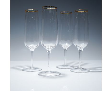 Set of four champagne flutes from the Martha Stewart Collection. Each flute is crafted from clear glass and features a gilt t