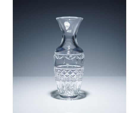 Crafted from clear crystal, the vase features a flared rim and a tapering form with criss-cross and foliate cut decoration al