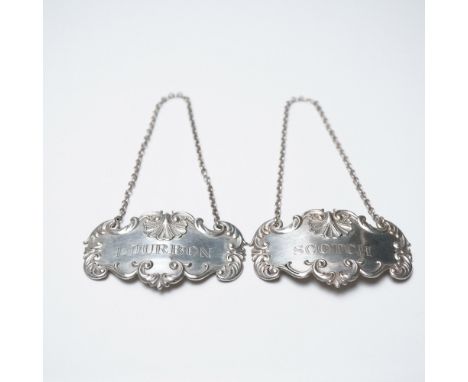 This pair of sterling silver liquor decanter tags feature intricate scrolling designs with a shell motif at the top, framing 