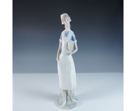 This Lladro figurine, titled Nurse (#1004603), portrays a poised and compassionate nurse in a traditional uniform, holding a 
