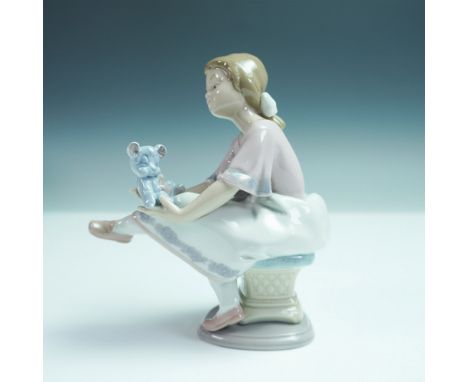 Lladro porcelain figurine Best Friend, number 7620, depicting a young girl seated on a cushioned stool, gently cradling a blu