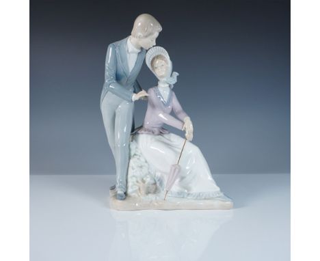 This Nao by Lladro figurine captures a charming Victorian-era couple in a tender moment, with a young gentleman leaning towar