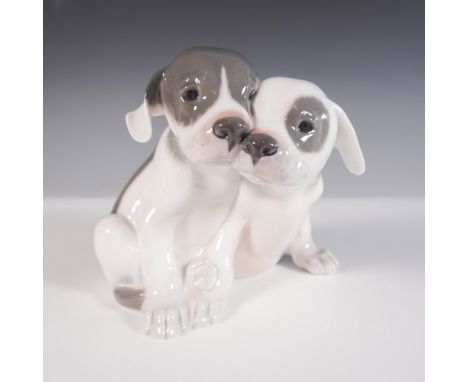 This endearing porcelain figurine by Royal Copenhagen features two puppies nuzzled together, their soft expressions rendered 