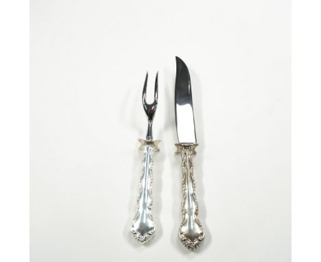 A finely crafted Reed &amp; Barton carving set featuring a knife and fork, each adorned with elegant sterling silver handles.