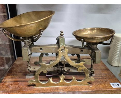 A set of Stevens of London brass shop scales mounted on a mahogany plinth with reccesses to take weights
