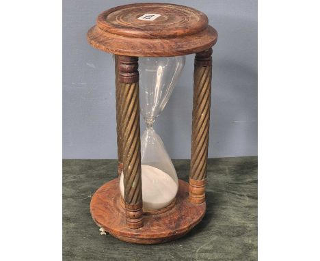 A sand timer held between the three spiral brass columns joining the wooden top and base.   H 32cms.