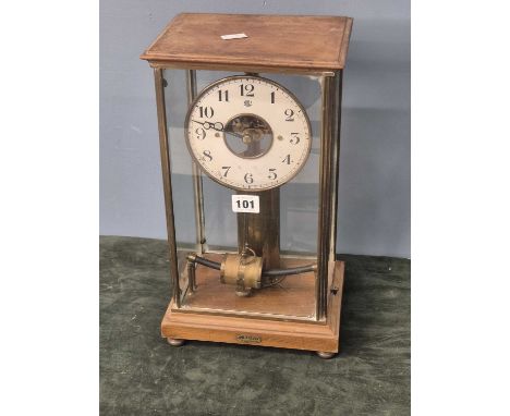 A Bulle electric clock with Arabic numerals to the white enamel chapter ring, the brass corners to the glazed case supported 