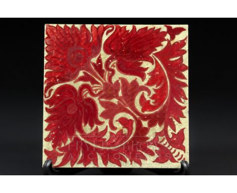 A Craven Dunnill ruby lustre tile, decorated with a William de Morgan design of stylised anthemion flowers and leaves, 15.1cm