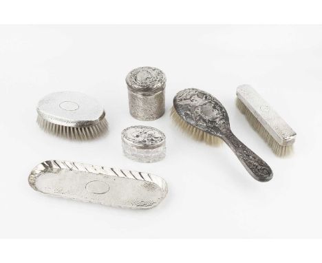 An Edwardian silver cylindrical box and cover, and a matching silver backed hairbrush, repoussé decorated with a mythical win
