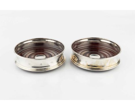 A pair of modern silver bottle coasters, with turned hardwood bases by Carr's, Sheffield 1998, 12.5cm wide. (2)