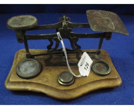 Small set of brass postal scales on serpentine wooden base with weights.