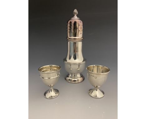 An Elizabeth II silver sugar shaker, Sheffield 1965, and two silver egg cups (3)
