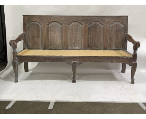 A George III limed oak country hall settle, circa 1770, five fielded panel back, inverted arms, ring turned supports, cabriol