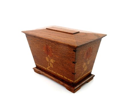 Arthur Simpson of Kendal, an Arts and Crafts oak and marquetry inlaid tea caddy, sarcophagus form, decorated with a stylised 