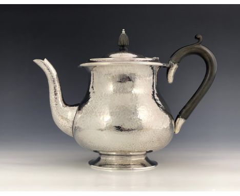 Sibyl Dunlop, an Arts and Crafts silver teapot, London 1930, planished, footed baluster form, with reeded finial, 23cm long, 