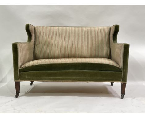 A late Victorian wing back salon settee, circa 1890, upholstered in green velvet and striped fabric, mahogany tapered block l