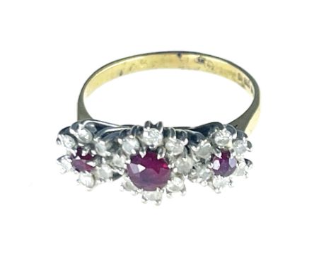 An 18 carat gold ruby cluster ring, three main stones within diamond clusters, 4.9g